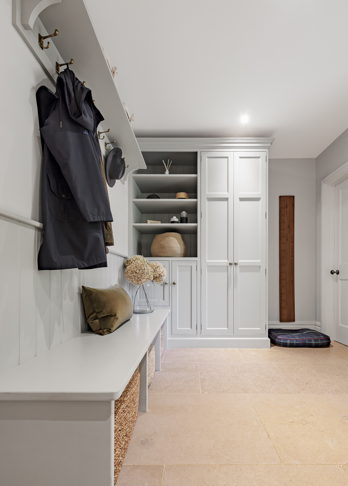 Painted boot room with coat hooks, bench seating and tall fitted storage