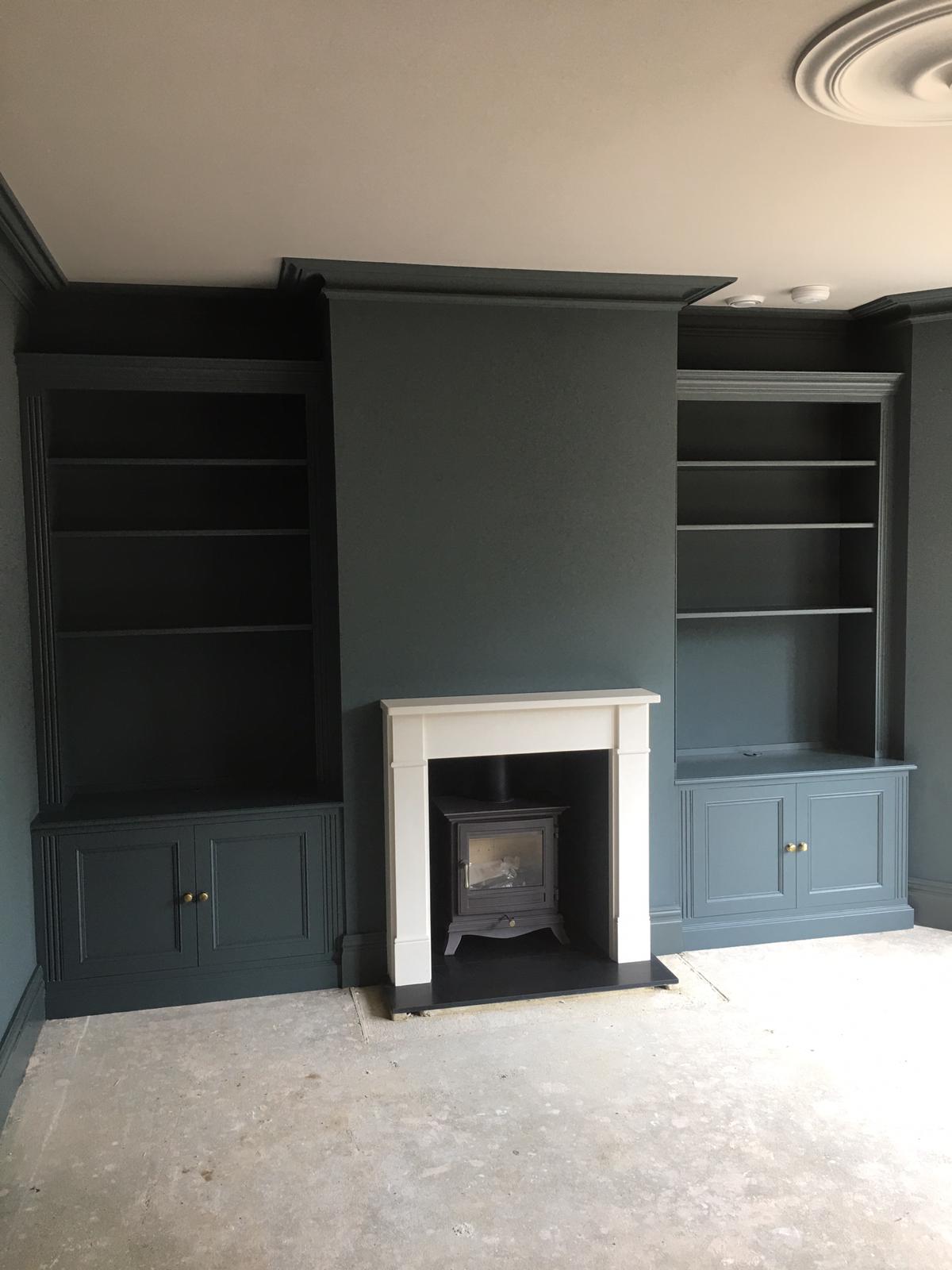 Dark painted fitted alcove shelving and cupboards around a fireplace
