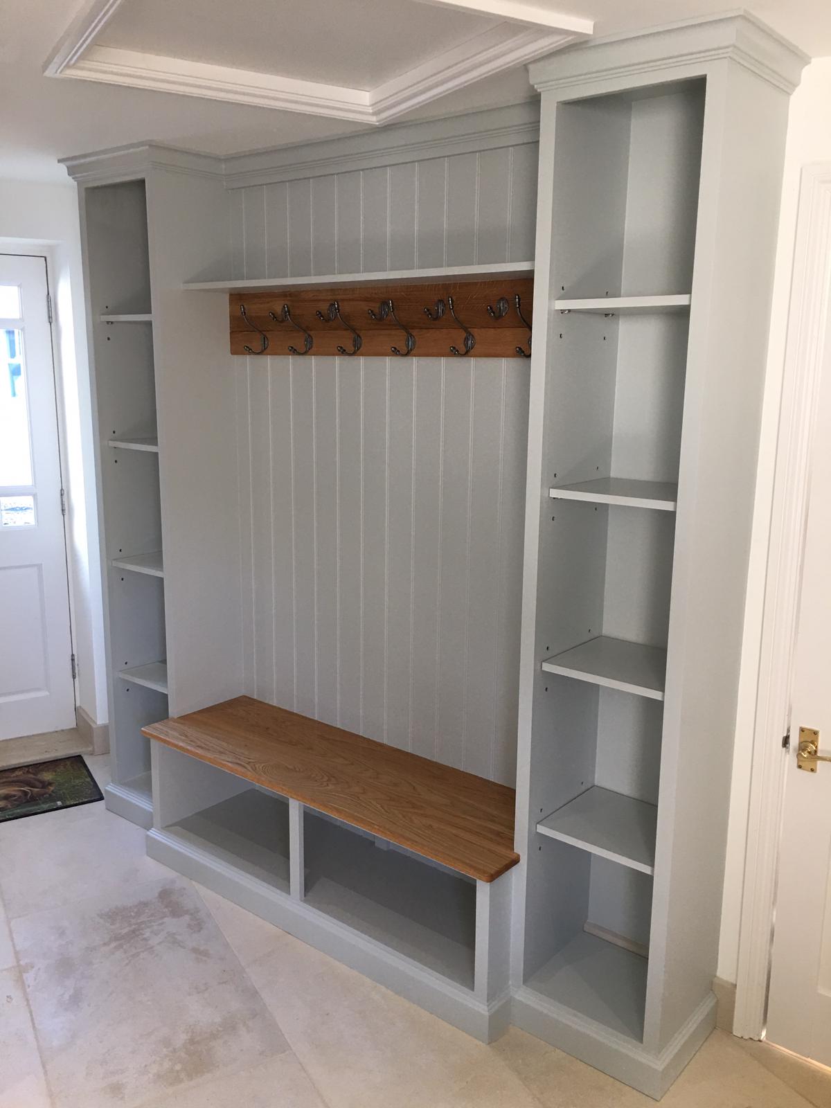 Grey painted boot room with open shelving, coat hooks and an oak bench