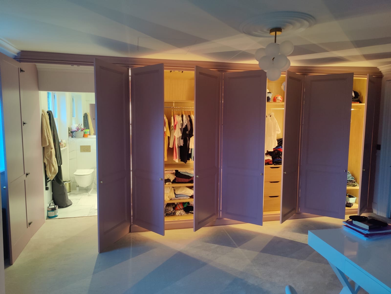Open fitted wardrobes showing tailored oak storage and an integrated doorway
